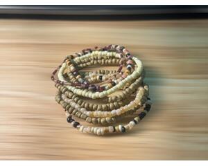There are 7 stretchy bracelets to this stack of seven brown and tan bracelets.